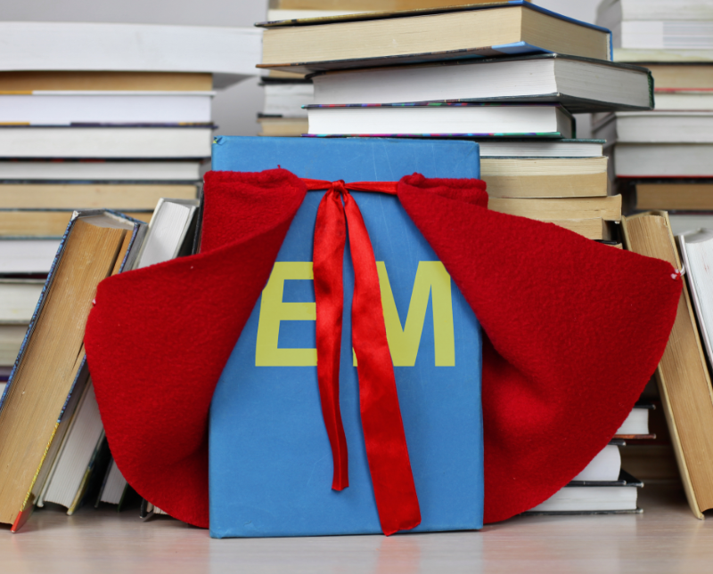 Book with EM on the cover wearing a superhero cape